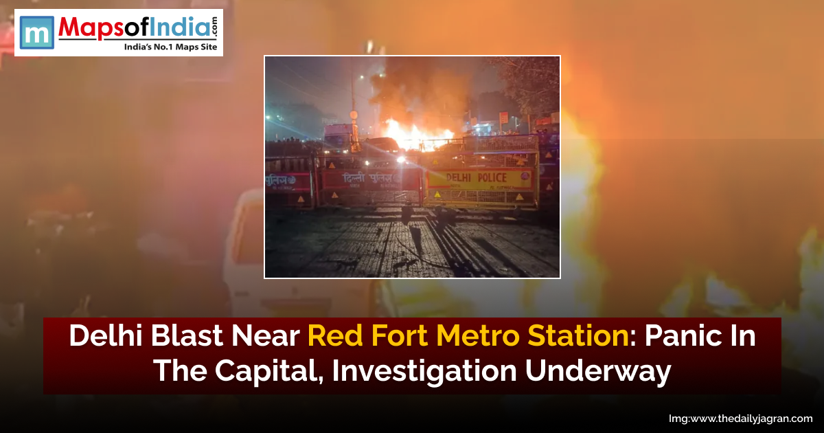 Delhi Police barricades and emergency vehicles block a street at night as flames and smoke rise from a blast near the Red Fort Metro Station in Delhi.