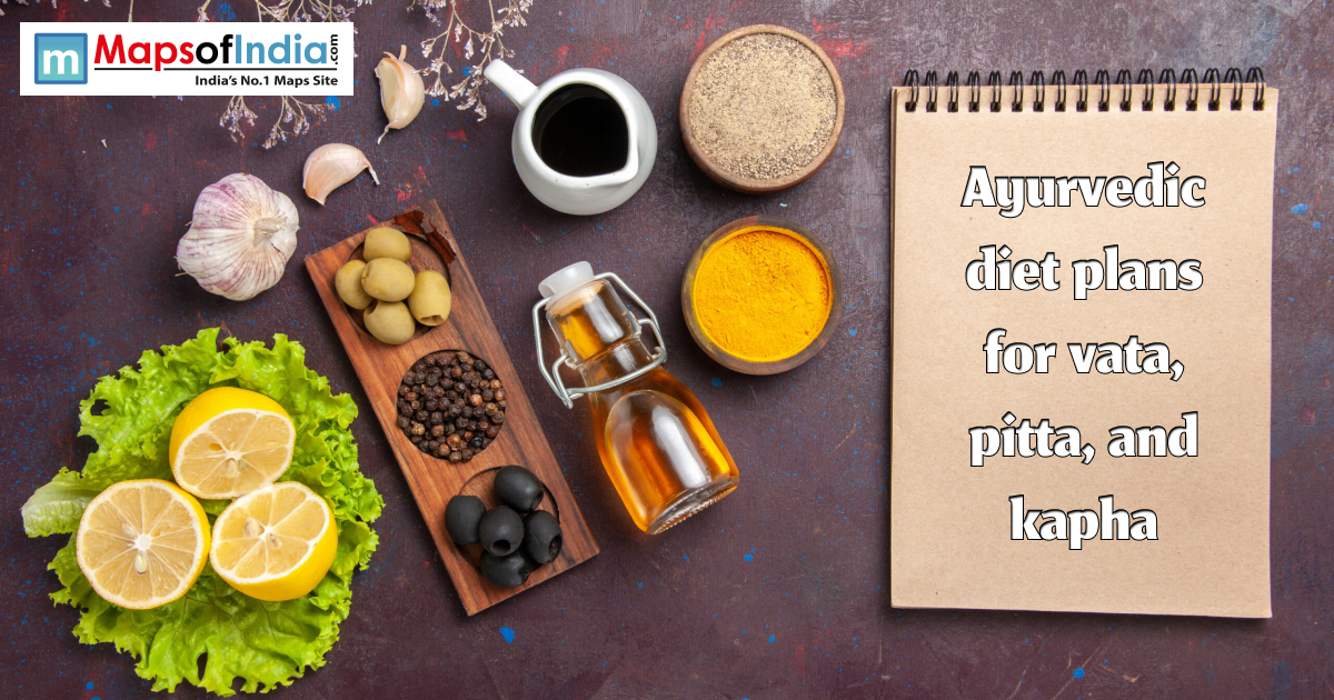 Flat lay of Ayurvedic foods and spices including lemons, lettuce, garlic, olives, oil, turmeric, and pepper beside a notebook reading “Ayurvedic diet plans for vata, pitta, and kapha.”