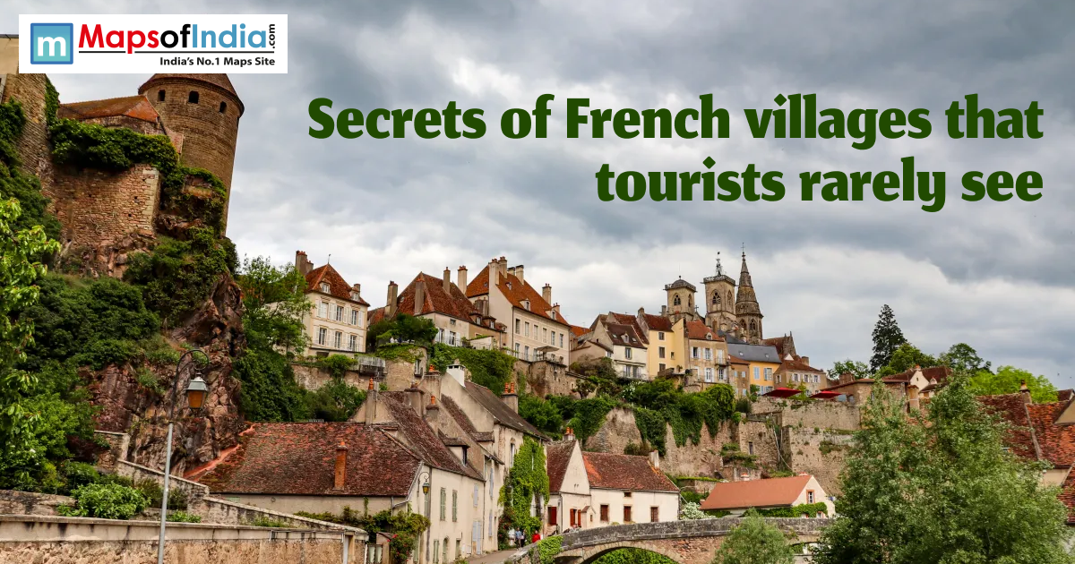 Hillside view of a hidden French village with stone tower, colorful houses, church spires, and a bridge under a cloudy sky.